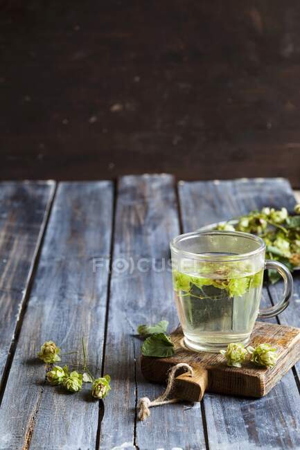 Houblon thé dans une tasse en verre sur une planche à découper — Photo de stock