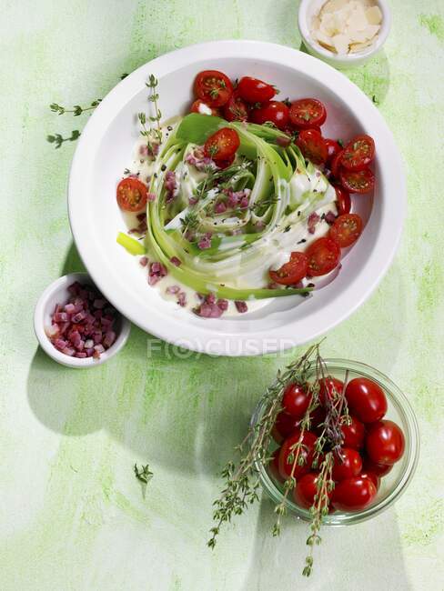 A leek nest with diced bacon, plum tomatoes and thyme — Stock Photo