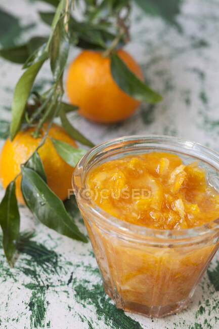Marmelade de mandarines dans un pot et fruits frais avec des feuilles — Photo de stock
