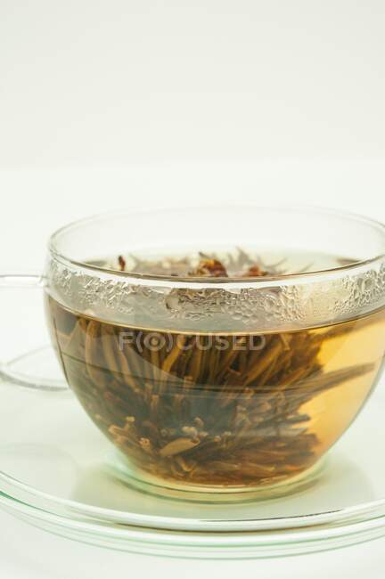 Weißer Tee mit einer blühenden Blume in einer Glasschale — Stockfoto