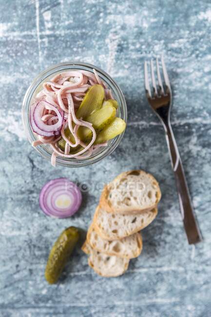Sausage, red onion and gherkin salad in glass jar with baguette slices — Stock Photo