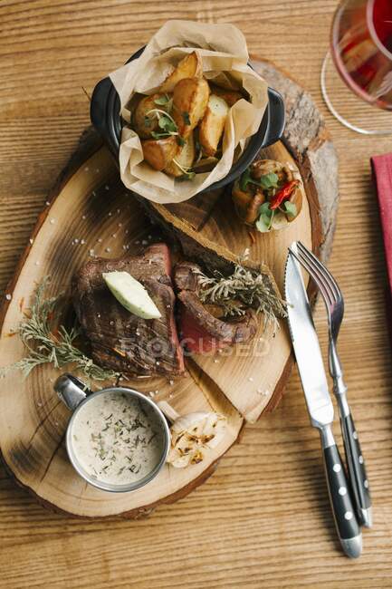 Steak mit Bratkartoffeln und Pilzsoße auf Baumscheibe serviert — Stockfoto
