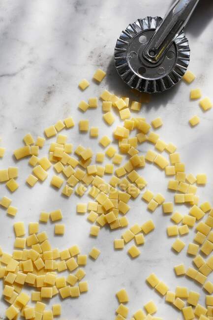 Pâtes carrées non cuites avec coupe-pâte sur fond de marbre — Photo de stock