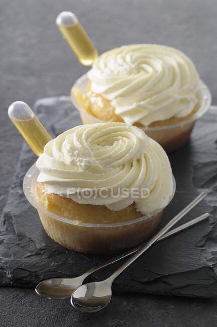 Rum baba with cream in plastic bowls — Stock Photo