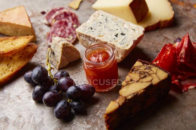 Fuente de aperitivos con diferentes tipos de queso, salami, uvas y pan - foto de stock