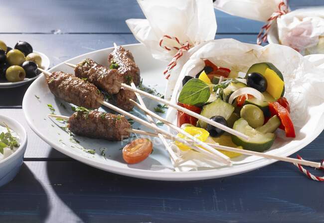 Cevapcici and vegetables wrapped in paper on a plate — Stock Photo