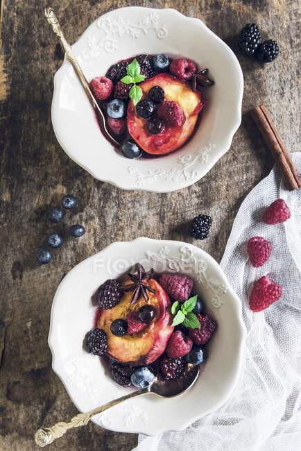 Жареные ягоды и персики в мисках — стоковое фото