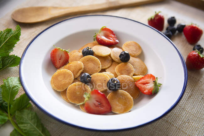 Minipancakes cereal in a bowl with milk and fruit — Stock Photo