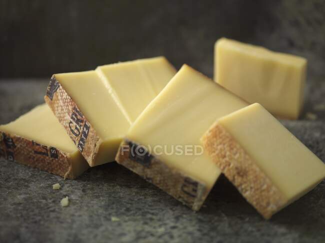 Several pieces of Gruyre cheese on stone surface — Stock Photo
