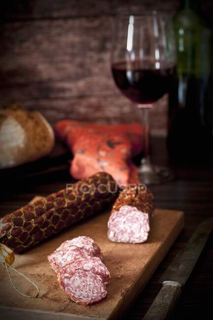 Salami de vino tinto ahumado hecho de cerdo y carne de res en una tabla de cortar de madera - foto de stock