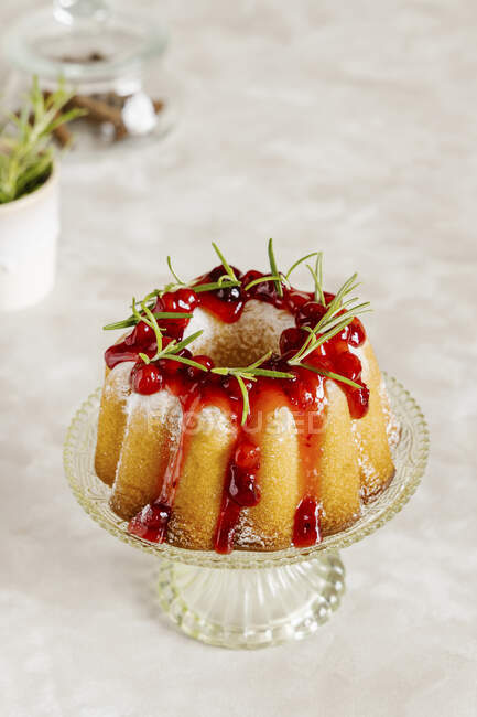 Vanilla bundt cake decorated with cranberry sauce and rosemary — Stock Photo