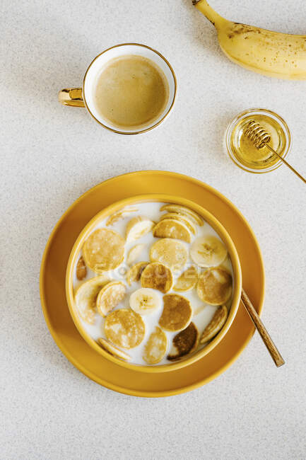 Pancake cereal in a bowl of milk with banana and honey — Stock Photo
