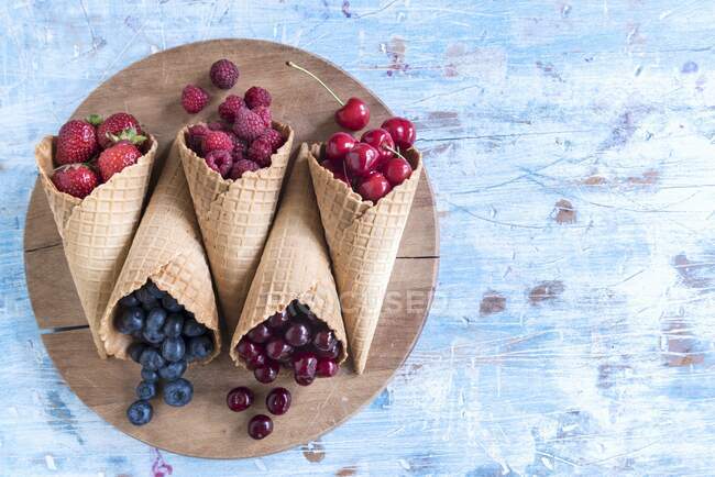 Різні ягоди та вишні в конусах морозива — стокове фото