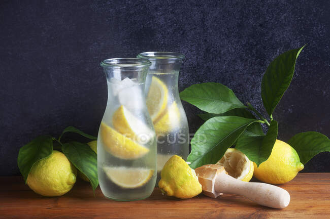 Домашний лимонад в стеклянных кувшинах со свежими лимонами и листьями — стоковое фото