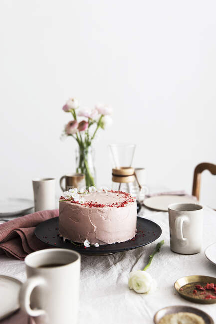 A strawberry cream cake on table laid for coffee — Stock Photo