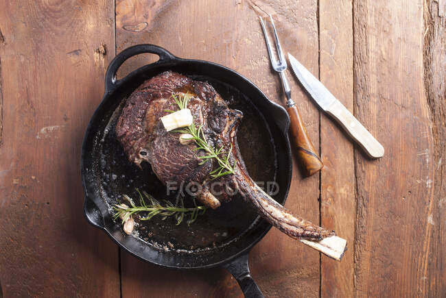 Tomahawk steak in cast iron pan, seasoned with butter and rosemary — Stock Photo