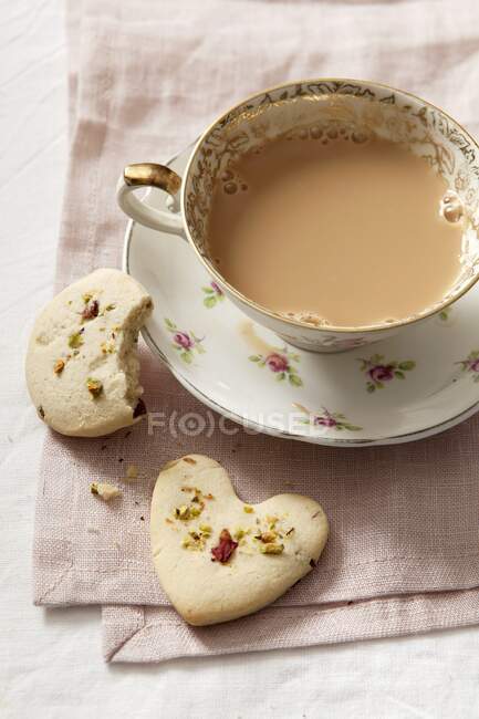 Biscoitos com pistache e pétalas de rosa secas, servidos com uma xícara de café — Fotografia de Stock