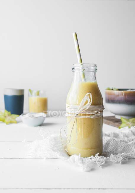 Манго и ананасовый смузи подаются в стеклянной бутылке с соломинкой — стоковое фото