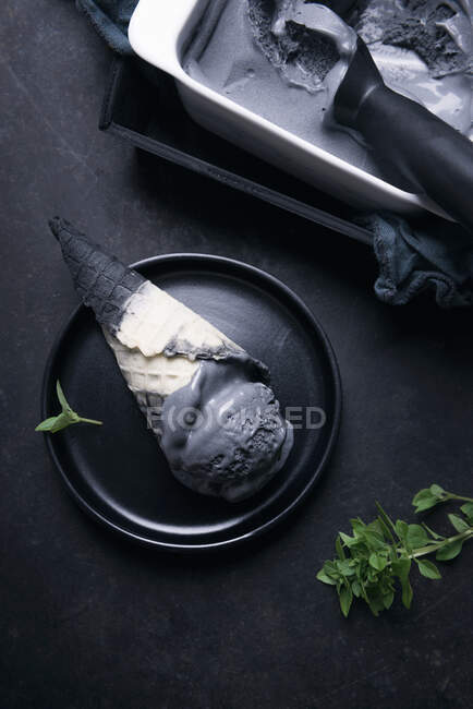Черное мороженое в двухцветном конусе — стоковое фото