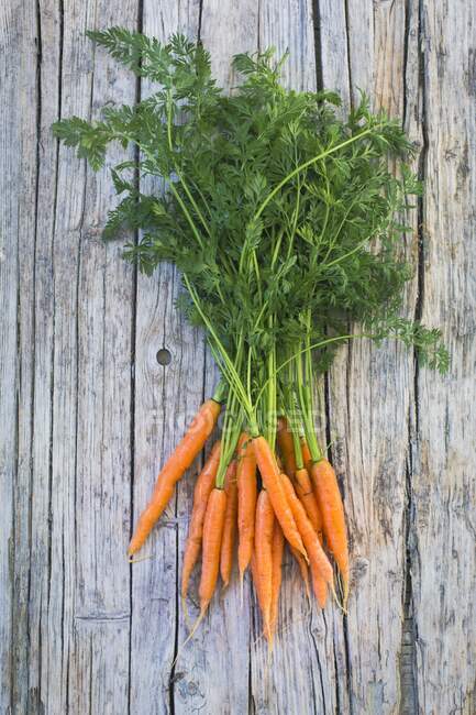 A bunch of baby carrots on a wooden surface (top view) — Stock Photo