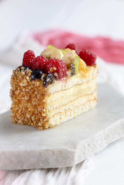 Classic vanilla and sponge fruit slice decorated with chopped nuts — Stock Photo