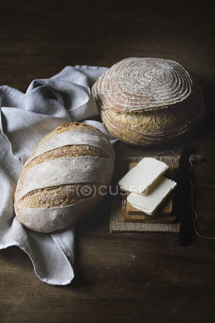 Two different bread loaves with butter on mini wooden board — Stock Photo