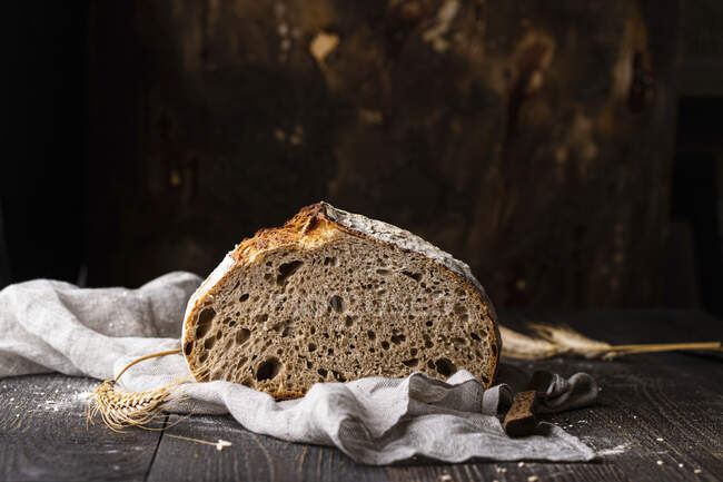 Sourdough bread on cloth with spikelet on wooden table — Stock Photo