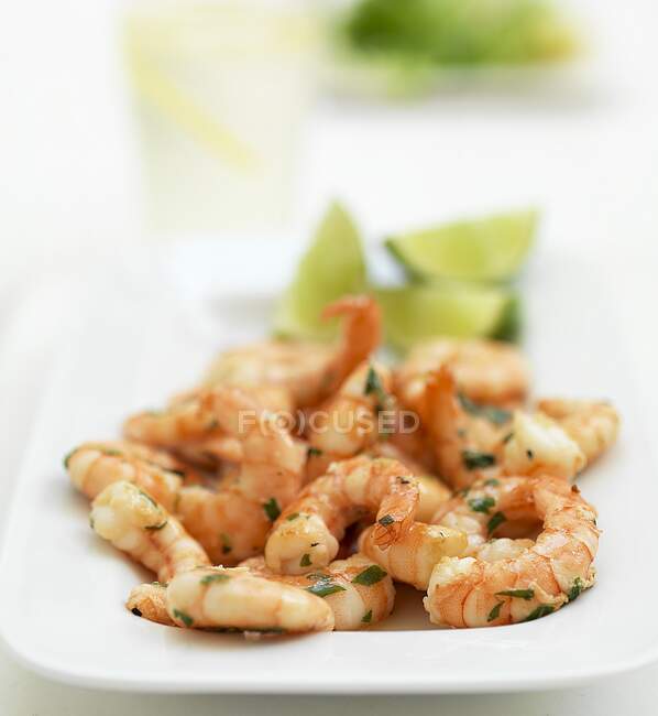 Prawns with lime wedges and herbs served on plate — Stock Photo