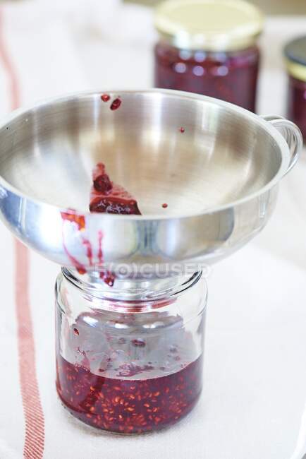 A jam jar with a metal funnel — Stock Photo