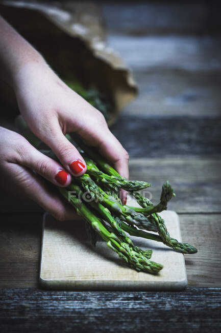 Fresh green asparagus with knife on wooden table — Stock Photo