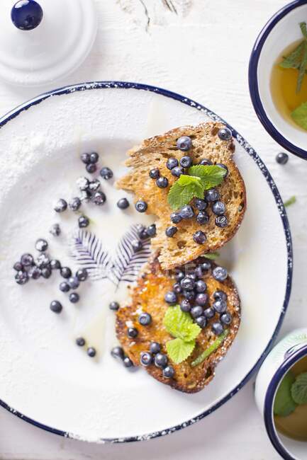 Toast mit Blaubeeren, Minze und Honig auf einem weißen Teller — Stockfoto