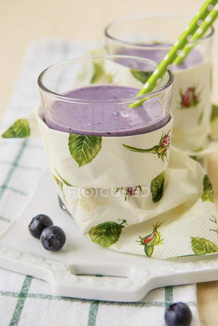 A blueberry smoothie in a glass with a straw — Stock Photo