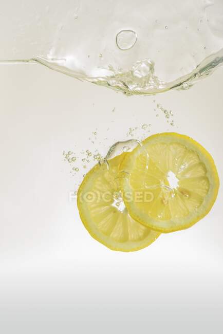 Лимонні шматочки падають у воду — стокове фото