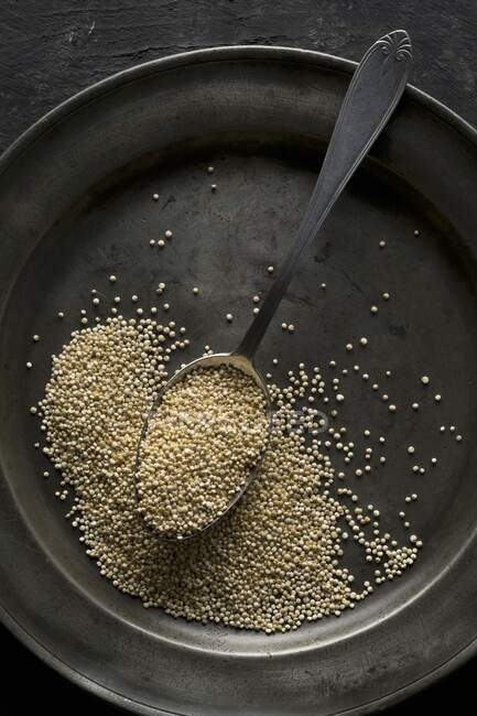 Quinoa con un cucchiaio su una vecchia piastra metallica — Foto stock
