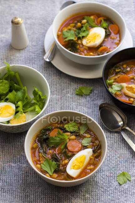 White bean soup with harissa, honey, egg and celery leaves — Stock Photo