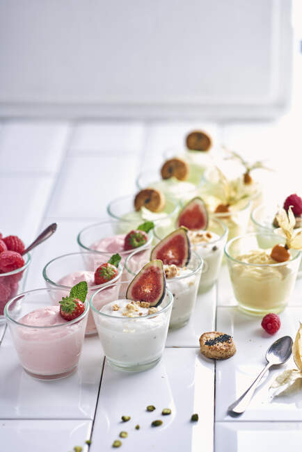 Різні десерти з йогуртами з фруктами в маленьких окулярах — стокове фото