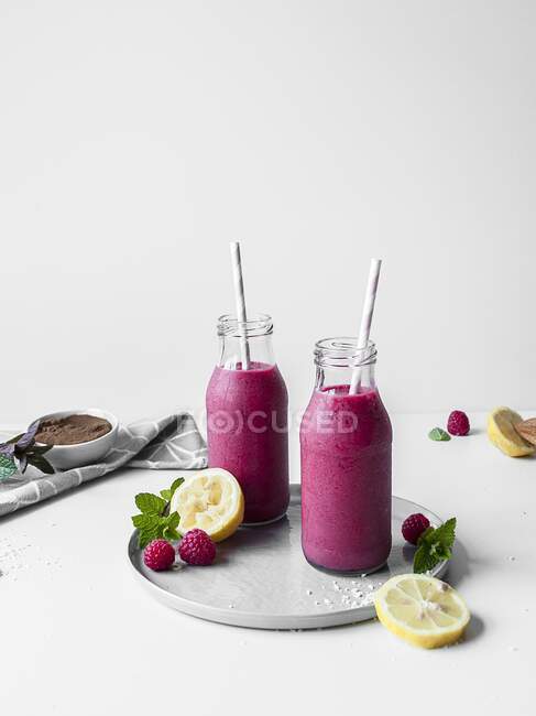 Rosafarbener Lakritze und Himbeer-Smoothie in Glasflaschen — Stockfoto