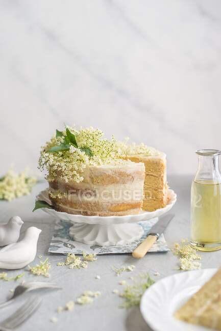 Torta de flor de saúco en un soporte de pastel, rebanada quitada - foto de stock