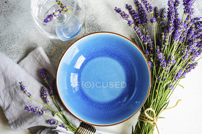 Літній стіл з синім посудом і столовими приборами, прикрашеними свіжими квітами лаванди — стокове фото