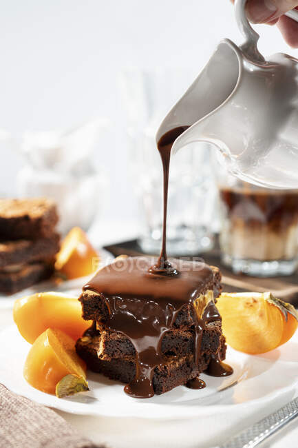 Molho de chocolate sendo derramado sobre brownies sem glúten — Fotografia de Stock