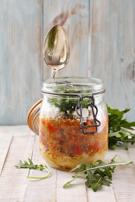Um caril de lentilha com cuscuz, queijo de ovelha e foguete em um frasco de vidro — Fotografia de Stock