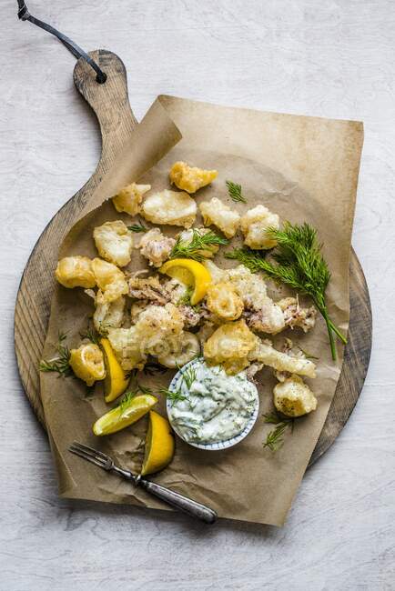 Жареный кальмар с лимонными клиньями и травяным соусом — стоковое фото