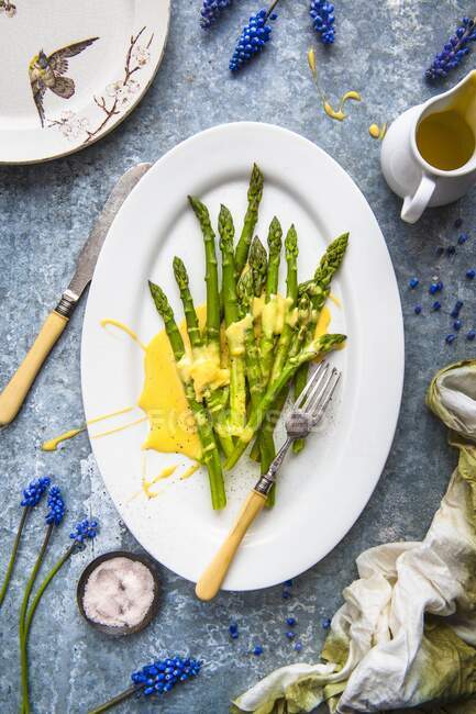 Green asparagus with hollandaise sauce on a serving plate (top view) — Stock Photo