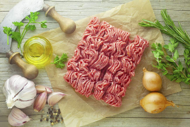 Raw minced meat with ingredients on a wooden surface — Stock Photo