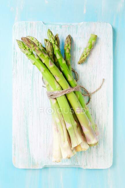 Fresh asparagus on wooden cutting board — Stock Photo