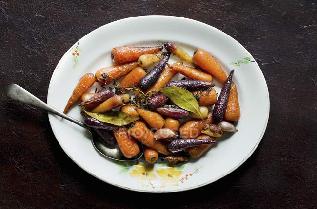 Glazed colourful carrots with garlic, laurel and thyme (top view) — Stock Photo
