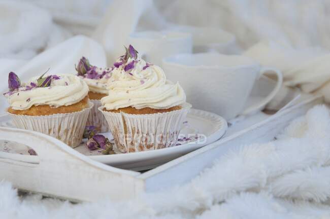 Cupcake alla vaniglia con petali di rosa secchi su vassoio bianco — Foto stock
