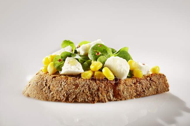 An open sandwich on farmhouse bread with lamb's lettuce, sweetcorn and pink pepper — Stock Photo