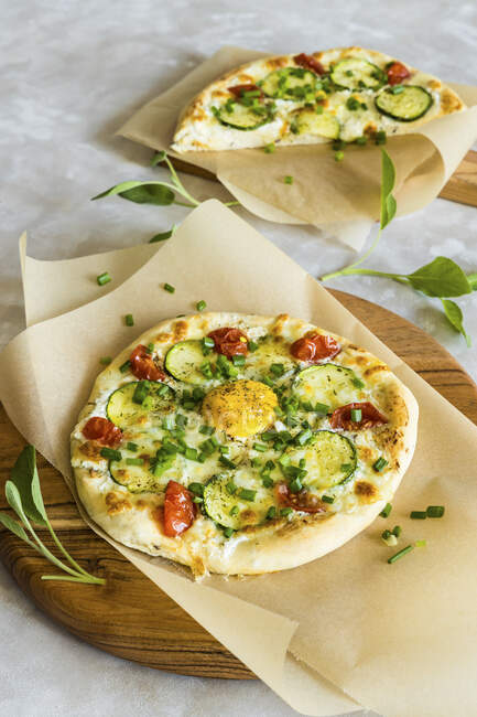 Pizza con queso crema sin lactosa, mozzarella, calabacín, tomates y yema de huevo - foto de stock
