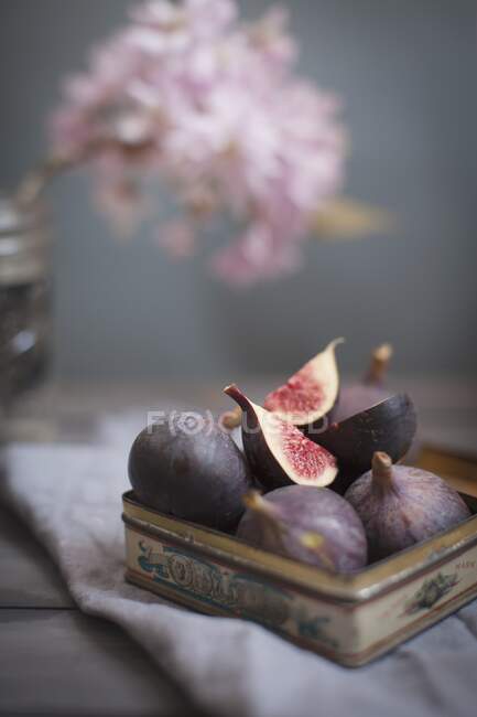 Vintage tin full of fresh figs topped with a quartered fruit — Stock Photo